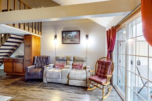 A spacious living area with a sofa, a rocking chair, a wooden cabinet, and a staircase. - Quiet 2BR Loft Condo - WILLOW VIEW - Peaceful (Branson)