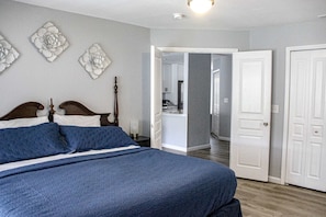 A bedroom with a large bed, a wooden headboard, and a door leading to a bathroom. - Classic 2BR Condo - SUN PORCH - Golf Course & Pool (Branson)