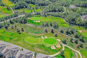 An aerial view of a golf course with multiple greens, sand bunkers, and surrounding trees. - Classic 2BR Condo - SUN PORCH - Golf Course & Pool (Branson)