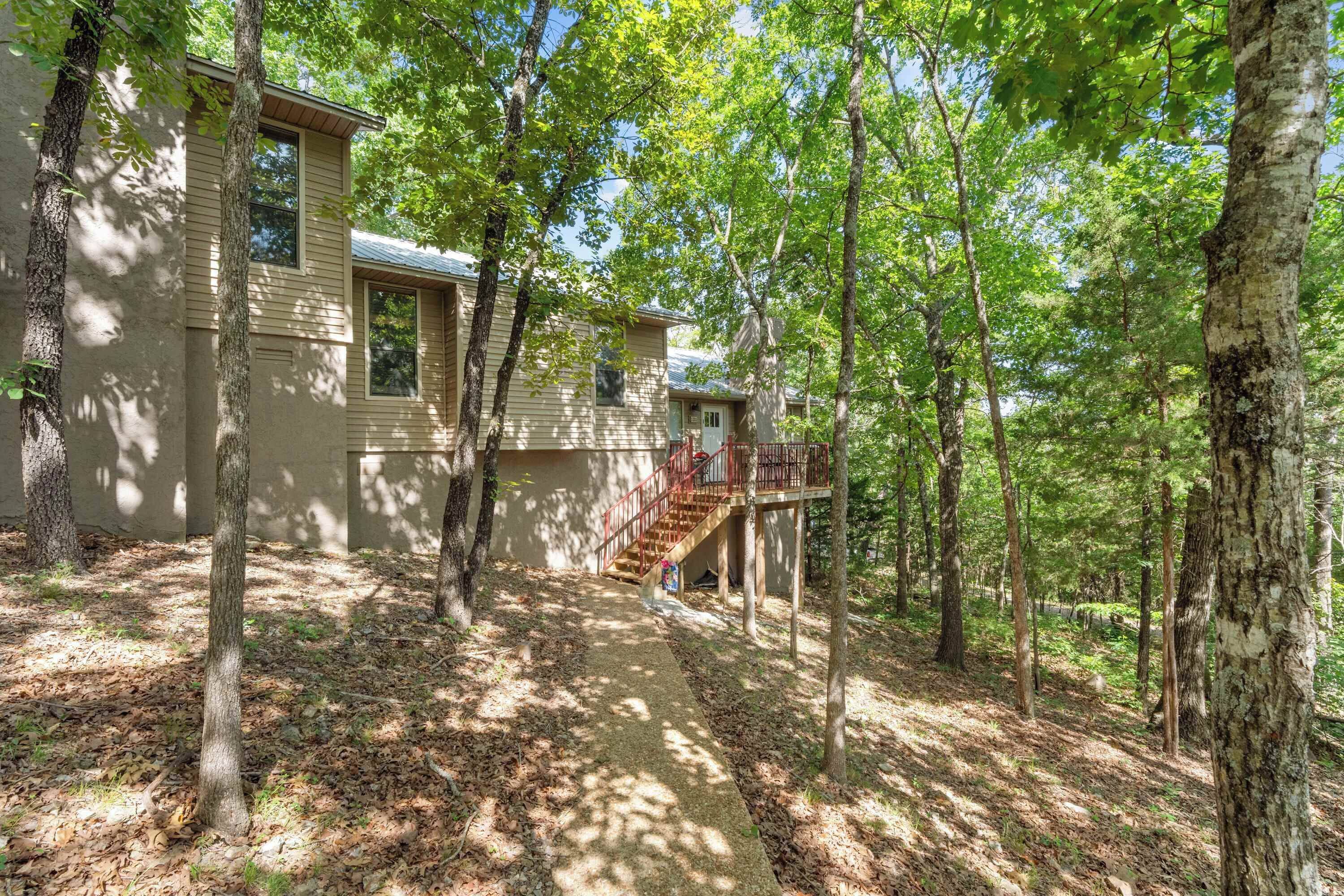 A house with a wooden deck and a staircase leading to a second-story balcony.