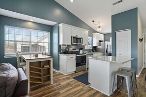 A kitchen with white cabinets, a microwave, stove, and a large island with stools. - 2BR Eagles Nest Condo - MOUNTAIN VIEWS - Pool (Branson)