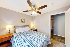 A bedroom with a bed, two bedside lamps, a ceiling fan, a nightstand, and a door leading to another room. - Bright 3BR Condo - MOUNTAIN VIEW - Near Pool (Branson)