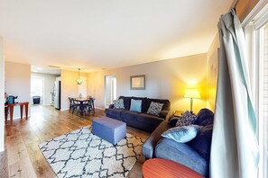 A living room with a sofa, ottoman, and a dining area with chairs and a table. - Bright 3BR Condo - MOUNTAIN VIEW - Near Pool (Branson)