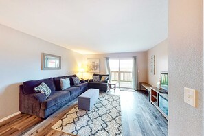 A living room with a sectional sofa, ottoman, and a TV stand. - Bright 3BR Condo - MOUNTAIN VIEW - Near Pool (Branson)