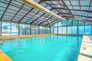 An indoor swimming pool with a glass ceiling, clear water, and a pool ladder. - GOLF VIEWS - 2BR Condo - Creek Views at Turnberry (Branson)