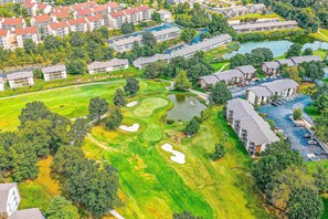 An aerial view of a golf course with a clubhouse, residential buildings, and a large body of water. - GOLF VIEWS - 2BR Condo - Creek Views at Turnberry (Branson)