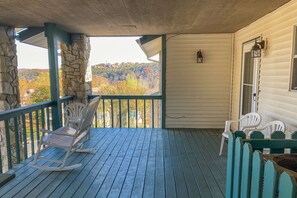 A porch with a stone column, a rocking chair, and a table with chairs. - Lake View 2BR Condo # POOLS # Golf # Pet-Friendly (Branson)