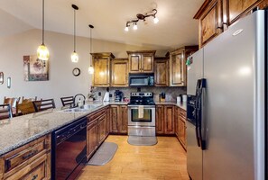 A kitchen with wooden cabinets, a stainless steel refrigerator, a built-in oven, and pendant lighting. - Lake View 2BR Condo # POOLS # Golf # Pet-Friendly (Branson)