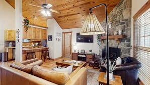 Ein gemütliches Wohnzimmer mit einer Ledersofa, einem Esstisch und einem Kamin aus Stein.