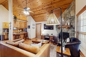 Ein gemütliches Wohnzimmer mit einer Ledersofa, einem Esstisch und einem Kamin aus Stein.