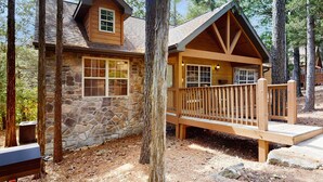 Eine Holzhütte mit Natursteinfassade, einer Holzdachterrasse und einer überdachten Veranda.