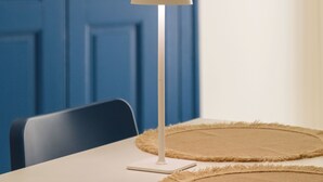 A room with a blue door, a white table, a lamp, and two woven placemats. - Southeast 13 - Moon House (Putignano)