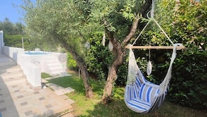 Een terras met een hangmat, zwembad en een tuin.