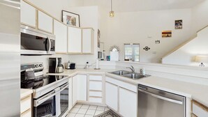 Een moderne keuken met inbouwapparatuur, een groot kookeiland met spoelbak en een trap naar een andere verdieping.