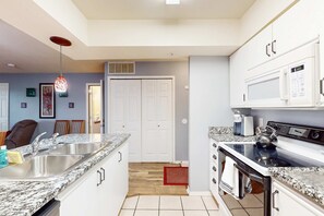 A kitchen with a double sink, stove, microwave, and white cabinets. - Golf View 2BR Condo - JACUZZI TUB - Branson (Branson)