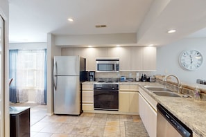 A modern kitchen with a refrigerator, microwave, stove, and dishwasher. - Sleek 2BR Condo - JETTED TUB - Pool & Creek Views (Branson)