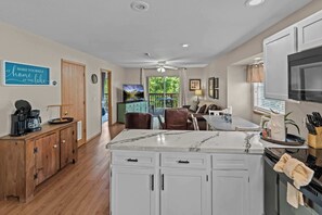 A modern kitchen with white cabinetry, a marble countertop, and a dining area with a view of the outdoors. - Serene 2BR Condo - Ozark views - Pool & Hot Tub (Branson)