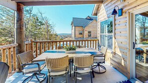 Eine Holzterrasse mit Tisch und Stühlen, einer Geländer und Blick auf ein Haus im Hintergrund.
