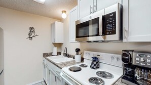 Une cuisine équipée d’une cuisinière blanche, d’un four à micro-ondes et d’une machine à café.