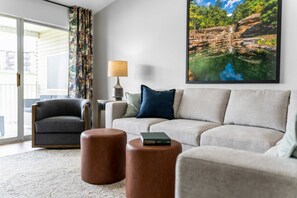 A living room with a sofa, armchair, two ottomans, a lamp, and a framed picture on the wall. - Peaceful 2BR Condo - DUCK POND VIEWS - Branson (Branson)