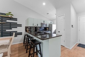 A modern kitchen with a central island, bar stools, a microwave, and a refrigerator. - Peaceful 2BR Condo - DUCK POND VIEWS - Branson (Branson)