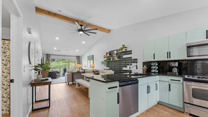 Een moderne keuken met een centraal eiland, roestvrijstalen apparatuur en lichtkleurige kasten.