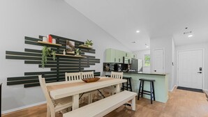 Een moderne keuken met een eethoek, houten vloeren en een groene accentmuur.
