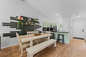 A modern kitchen with a dining area, wooden flooring, and a green accent wall. - Peaceful 2BR Condo - DUCK POND VIEWS - Branson (Branson)