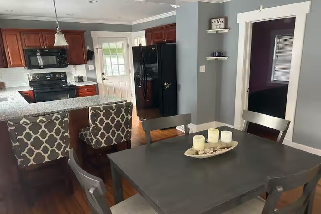 A modern kitchen with a central island, built-in appliances, and a dining area with a table set for four.
