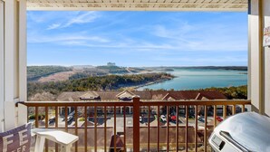 En balkon med udsigt over en sø, bygninger og et fjerntliggende slot.