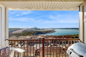 A balcony with a view of a lake, buildings, and a distant castle. - LAKE VIEW 3BR Condo - Pool & Entertainment Ready (Branson)