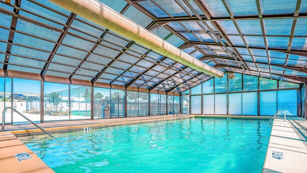 En indendørs swimmingpool med glasloft, klart vand og udsigt ud