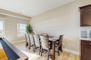 Uma sala de jantar com uma mesa retangular, seis cadeiras e um vaso de planta.