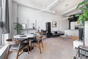 A modern living space with a dining area, a sofa, a coffee table, and a kitchen area. - Luxury 2 Bedrooms 2 Bath London Flat 6 Guests (London)