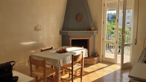 Zona pranzo con tavolo, sedie, camino e vista sull'esterno.