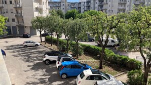 Un parcheggio con diverse auto, alberi e edifici residenziali sullo sfondo.