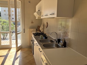 A kitchen with a large window, a stove, a sink, and cabinets. - Ostuni Home with Terrace & Free Parking – Near Old Town (Ostuni)