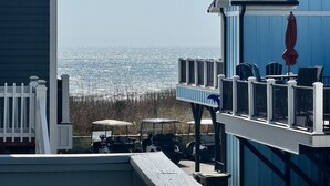 Ein Küstengebäude mit Balkon und Meerblick, ausgestattet mit Sitzgelegenheiten im Freien und einer Aussicht auf den Strand.