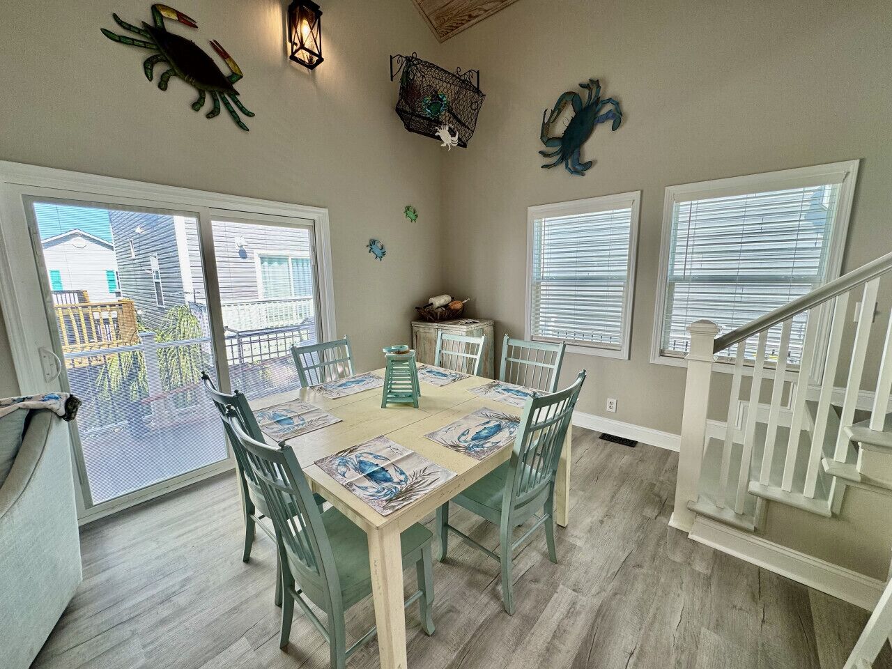 A dining area with a table set for four, surrounded by chairs, and a staircase leading to an upper level.