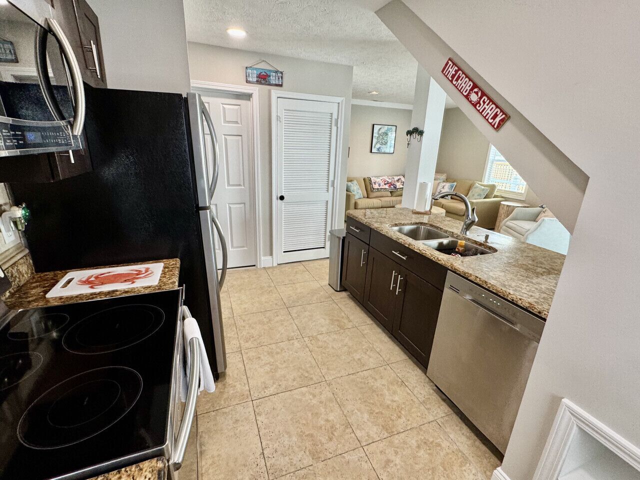 A kitchen with a black refrigerator, stainless steel dishwasher, and granite countertops.