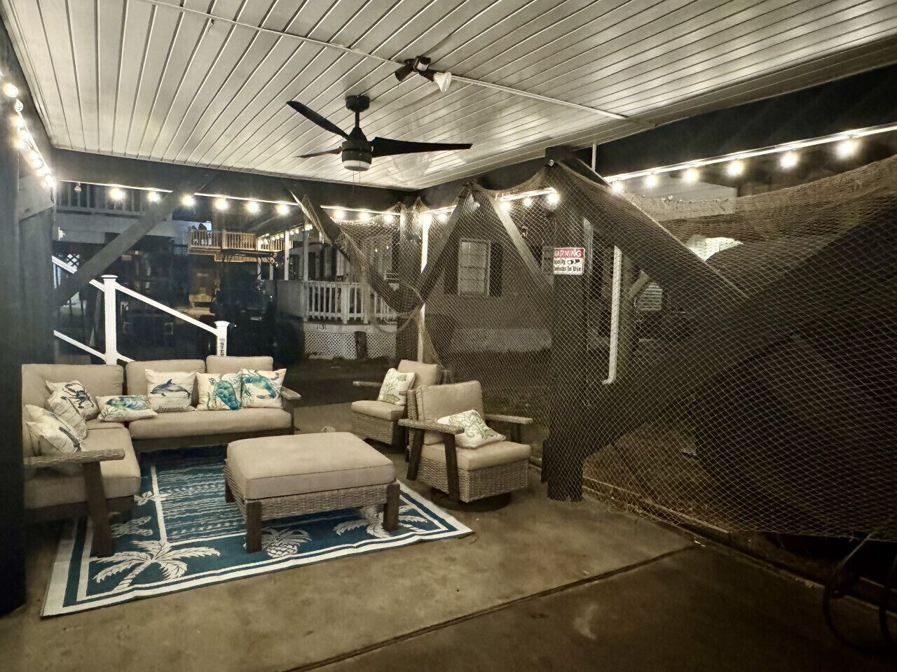 Un espacio interior acogedor con ventilador de techo, luces colgantes, un sofá con cojines y una silla.
