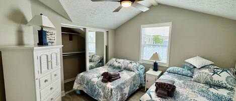 A bedroom with two beds, a ceiling fan, a walk-in closet, and a window with blinds.