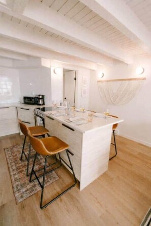 A modern kitchen with a central island, bar stools, a microwave, and a coffee maker. - Modern Luxe Ski In/Out Sleeps 6 within Walking Distance to Dining at the Base! (Steamboat Springs)