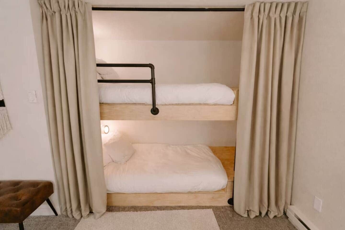 Habitación con literas, una banca y una lámpara.