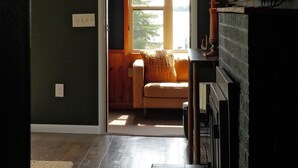 A room with a wooden floor, a window, a sofa, and a lamp. - Hessel Bay Main Cabin : Idyllic Les Cheneaux Islands waterfront cabin sleeps 8 (Hessel)