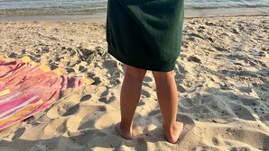 A person standing on a sandy beach wearing a green hoodie with 'Hessel Bay Cabins' written on the back. - Hessel Bay Cabin 1:  Lake Huron waterfront resort cabin sleeps 2. (Hessel)