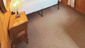 A wooden-paneled room with a bed, a bedside lamp, a framed picture on the wall, and a window with curtains. - Hessel Bay Cabin 2:  Lake Huron waterfront resort cabin sleeps 2. (Hessel)