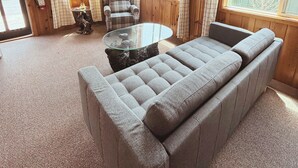 A room with a ceiling fan, a sofa, a chair, a glass table, and a window with a view. - Hessel Bay Cabin 2:  Lake Huron waterfront resort cabin sleeps 2. (Hessel)