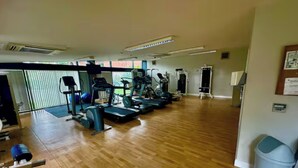 A gym with exercise equipment, a wooden floor, and a large window. - 2br city side apartment (Belfast)