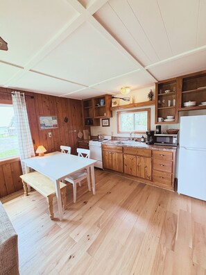Une cuisine avec des meubles de rangement en bois, un réfrigérateur blanc, une cuisinière et une table à manger avec des chaises.